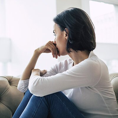 Eine Frau sitzt auf einem Sofa und schaut aus dem Fenster