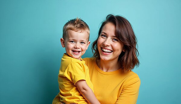 Eine Frau hält ein kleines Kind auf dem Arm. Beide Lächeln