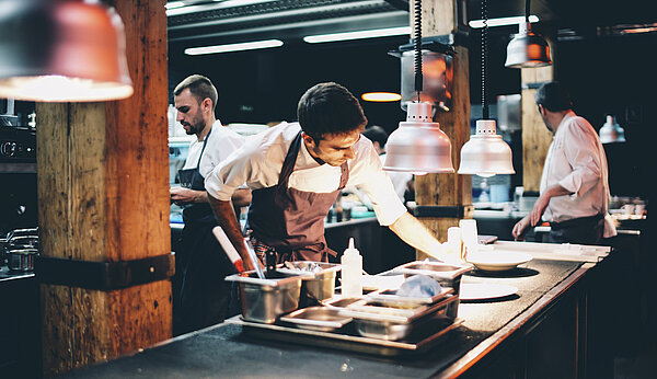 Köche bereiten in einer offenen Küche Speisen zu
