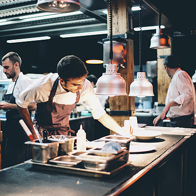 Köche bereiten in einer offenen Küche Speisen zu