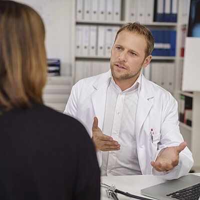 Ein Mann spricht mit einer Frau in einem Behandlungsraum