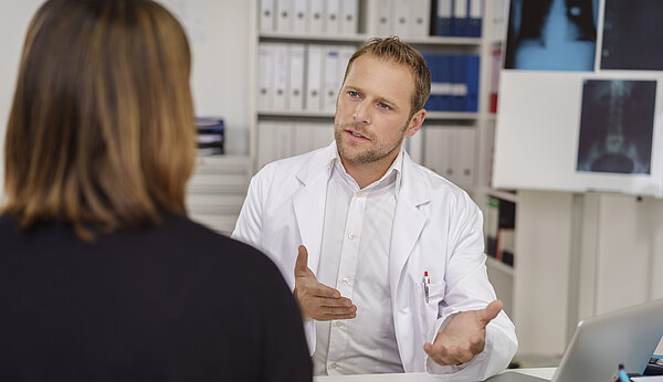 Ein Mann spricht mit einer Frau in einem Behandlungsraum
