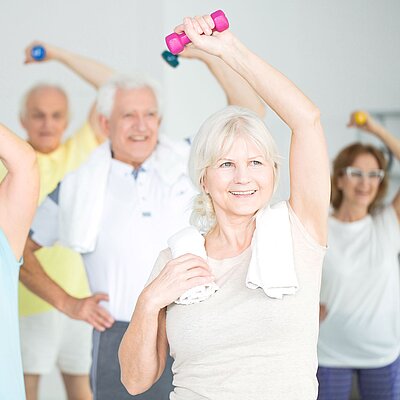 Eine Gruppe älterer Menschen trainiert mit kleinen Hanteln