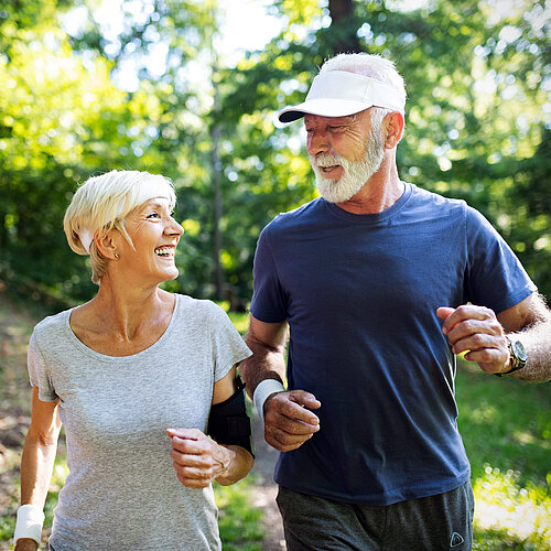 Eine ältere Dame und ein älterer Herr sind im Wald joggen