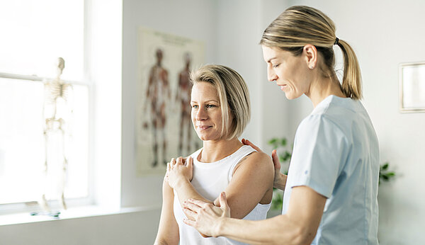 Eine Frau führt mit einer anderen Frau Übungen durch