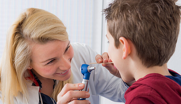 Ärztin untersucht den Hals eines Jungen