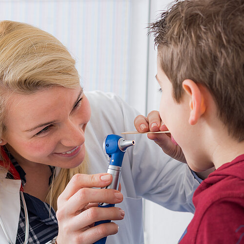 Ärztin untersucht den Hals eines Jungen