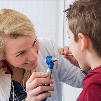 Ärztin untersucht den Hals eines Jungen