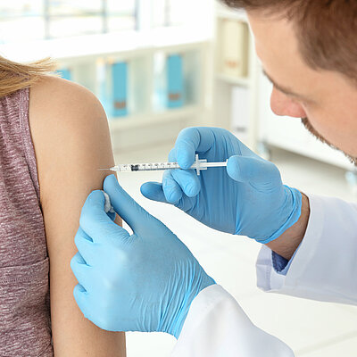 Eine Frau erhält eine Impfspritze in den linken Oberarm