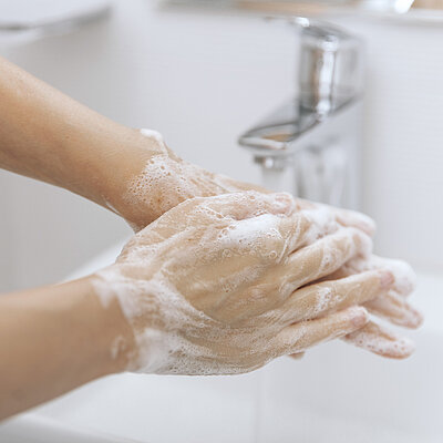 Hände werden unter laufendem Wasser gewaschen