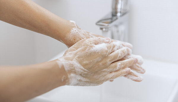 Hände werden unter laufendem Wasser gewaschen