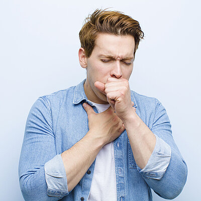 Ein Mann hustet und hält sich dabei den Brustkorb