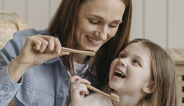 Eine Frau und ein kleines Mädchen putzen sich die Zähne