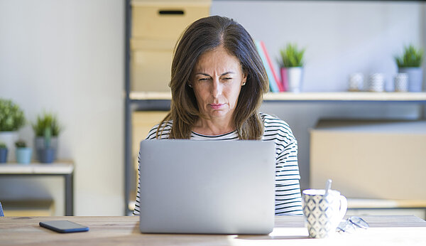 Eine Frau sitzt vor einem Laptop und schaut auf den Bildschirm