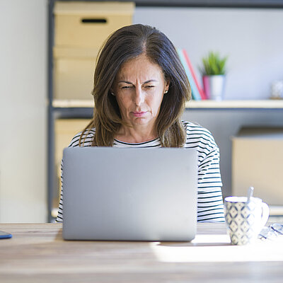 Eine Frau sitzt vor einem Laptop und schaut auf den Bildschirm