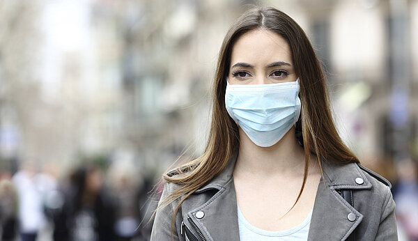Eine jüngere Frau mit medizinischer Maske vor Mund und Nase