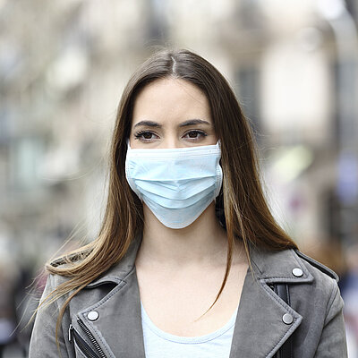 Eine jüngere Frau mit medizinischer Maske vor Mund und Nase